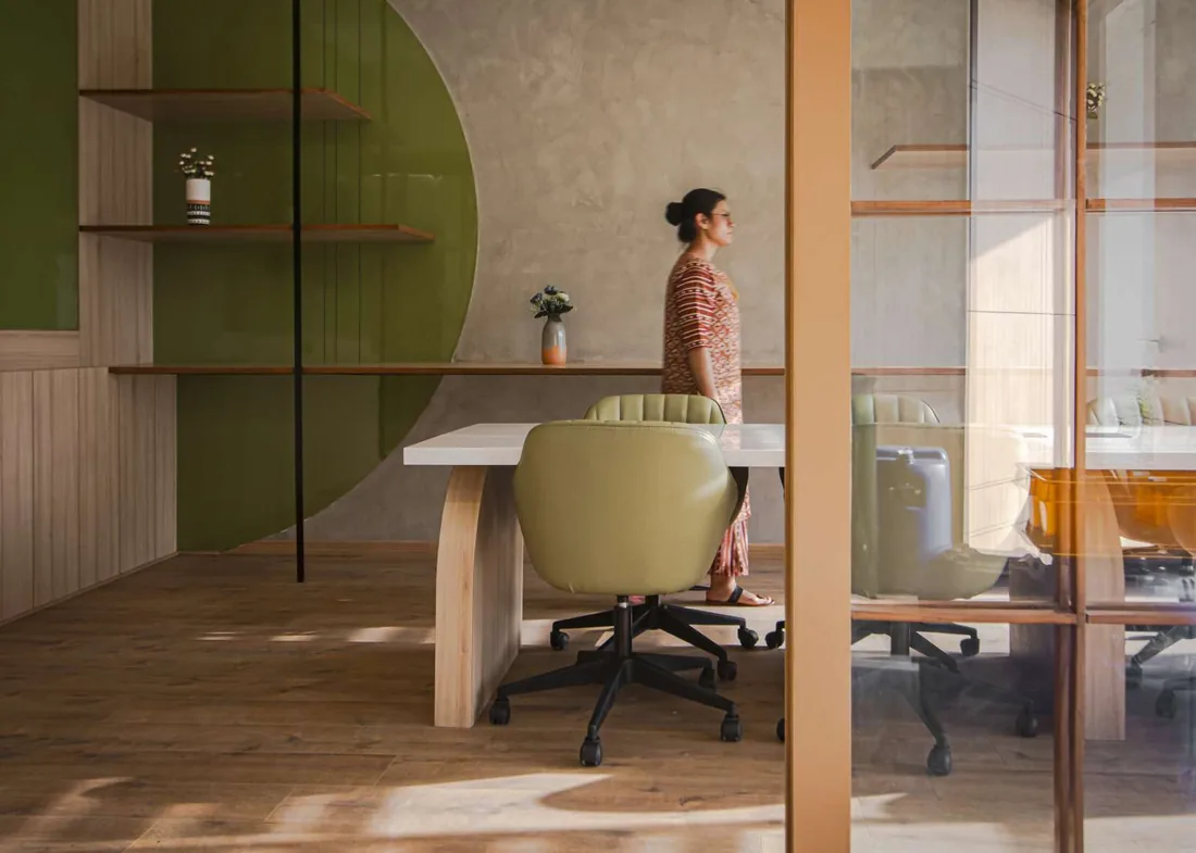 Office with a green arch wall, wooden desk and glass partitions