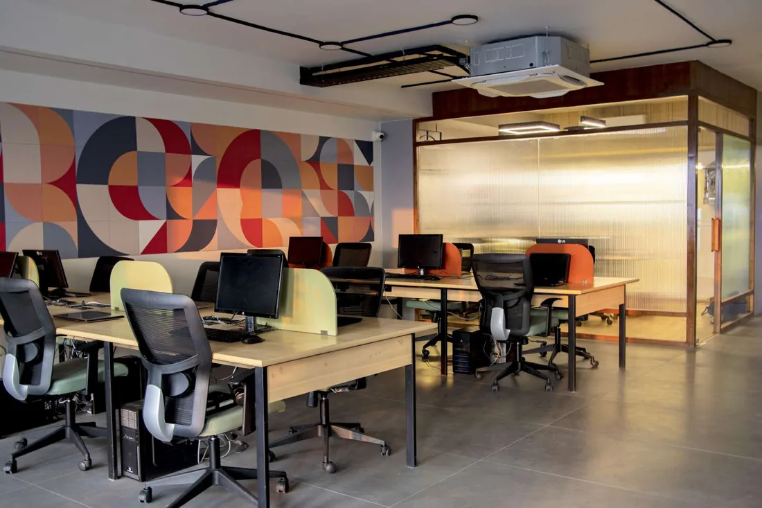 Open-plan office with a geometric mural and a fluted-glass cabin